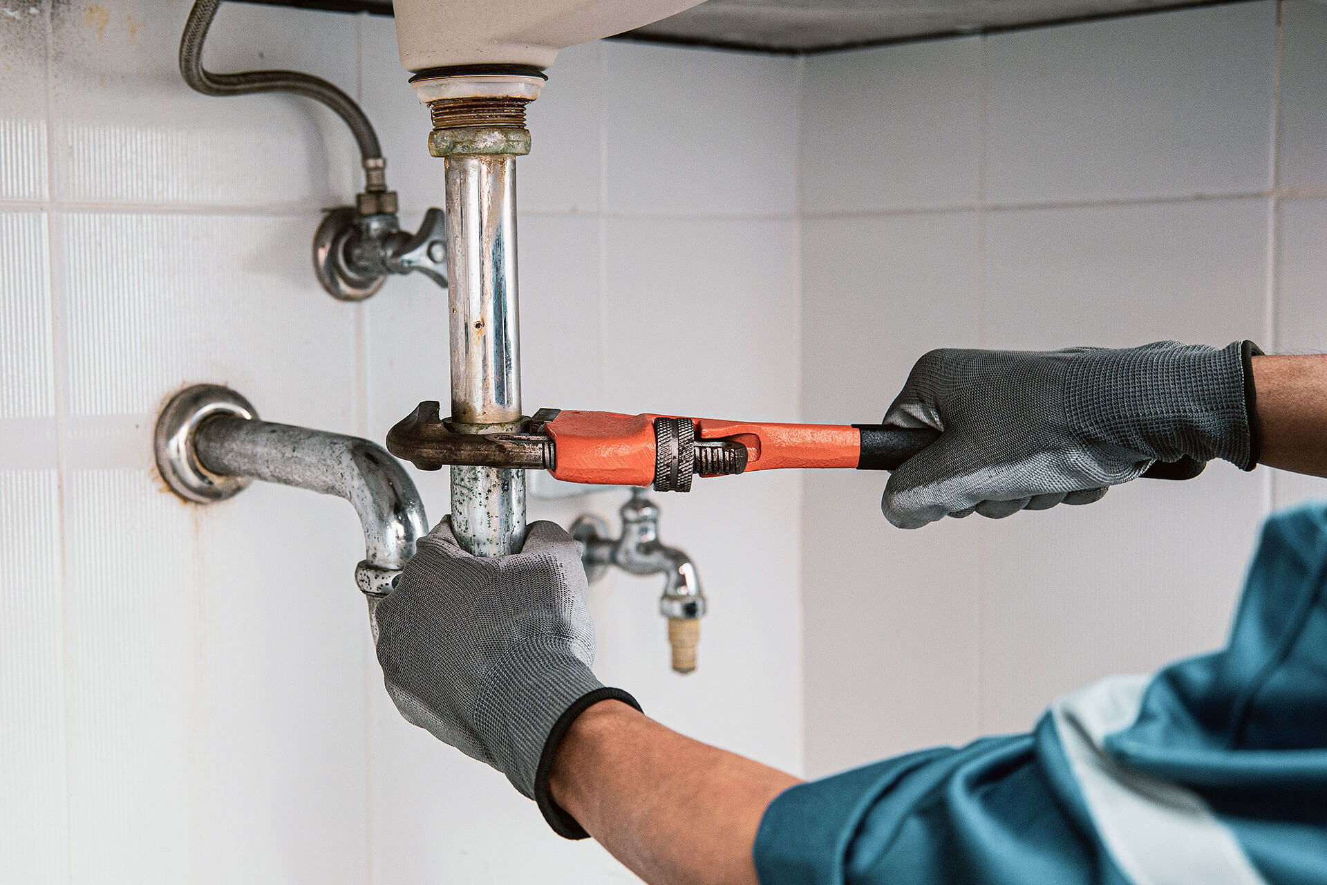 Plumber diagnosing a leak under a kitchen sink