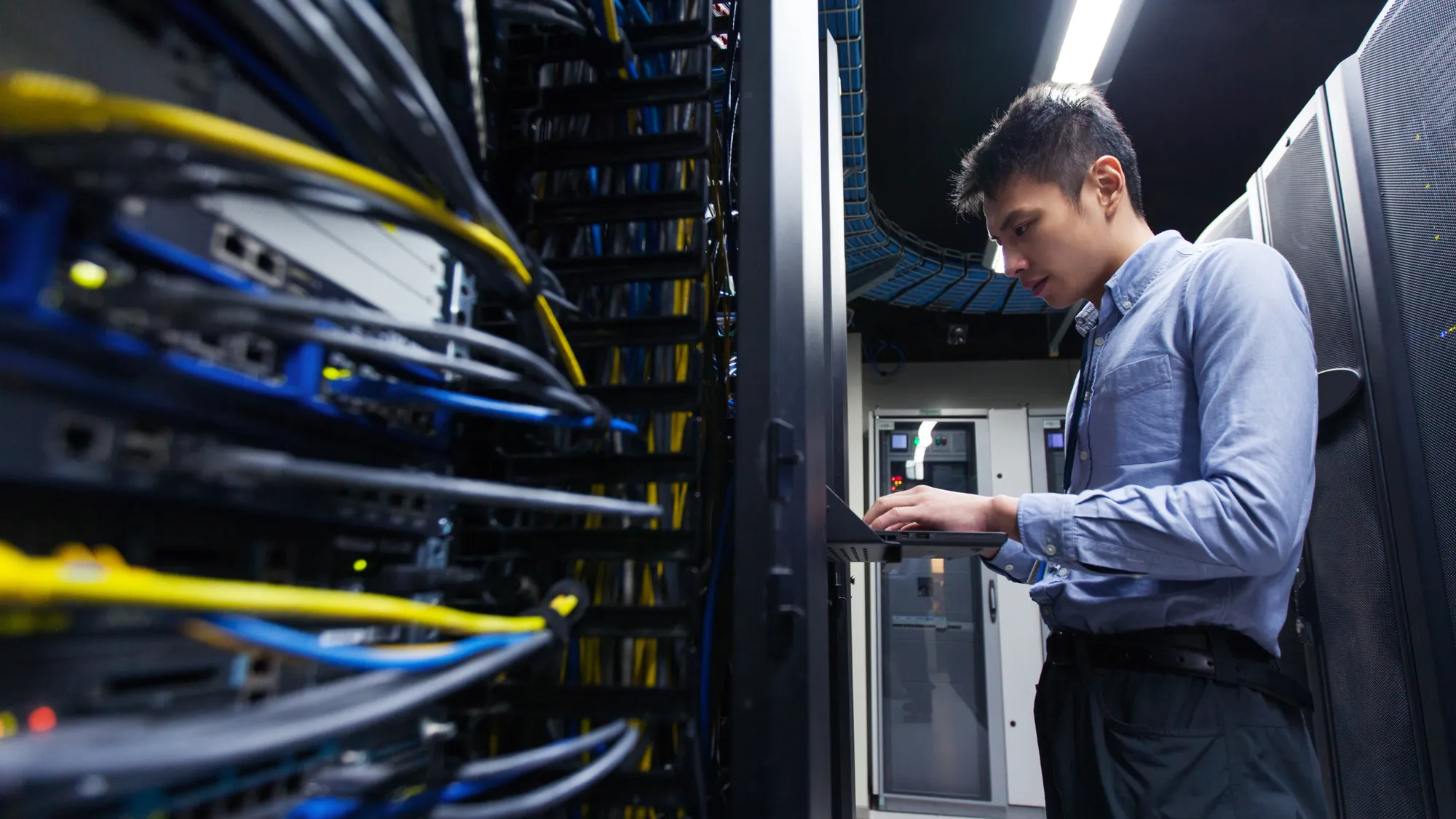 Technician working on network cabling inside a server room